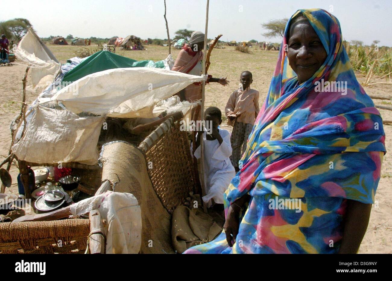 (dpa) - A woman stands next to the remains of her belongings in the refugee camp in Nyala, in the province of Darfur, Sudan, 13 July 2004. Arab militiamen are terrorising the local population. Stock Photo