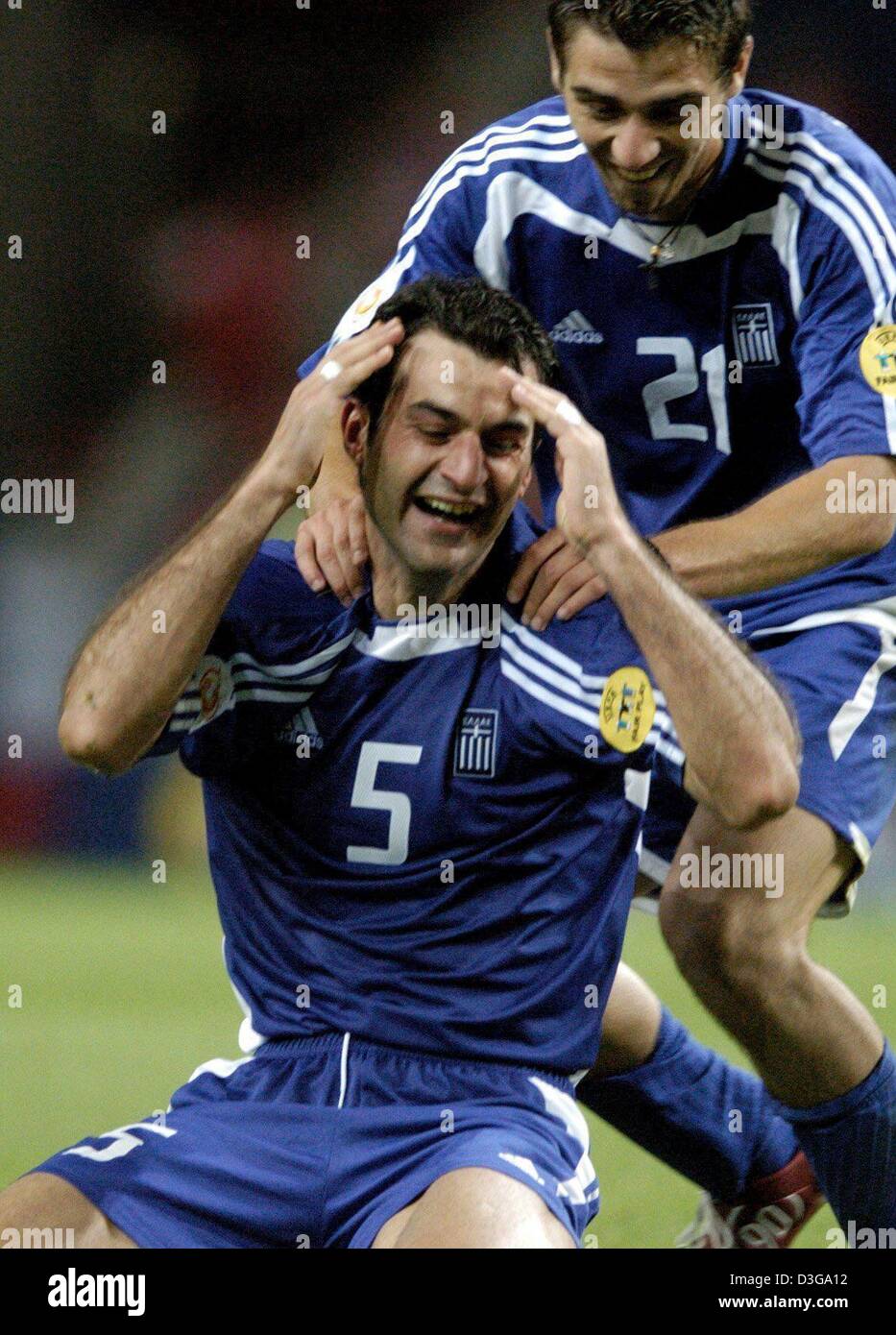 (dpa) - Greek defender Traianos Dellas (no 5) kneels on the pitch and cheers while being congratulated by his teammate Konstantinos Katsouranis after scoring the winning 1-0 silver goal during the Soccer Euro 2004 semifinal opposing Greece and the Czech Republic  in Porto, Portugal, 1 July 2004. Greece scored the goal during extra time in the 105th minute of the game and qualified  Stock Photo