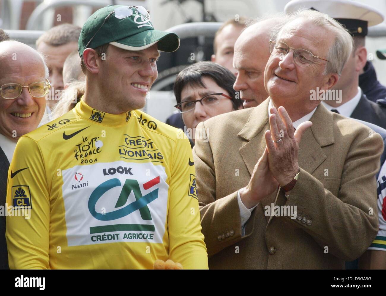 (dpa) - Norwegian cyclist Thor Hushovd of team Credit Agricole smiles after receiving the yellow jersey of the overall leader as Belgian king Albert II. applauds him after the second stage of the Tour de France in Namur, Belgium, 5 July 2004. The second and 197km long stage of the 91st Tour de France cycling race took the cyclists from Charleroi to Namur. A second place finish in t Stock Photo