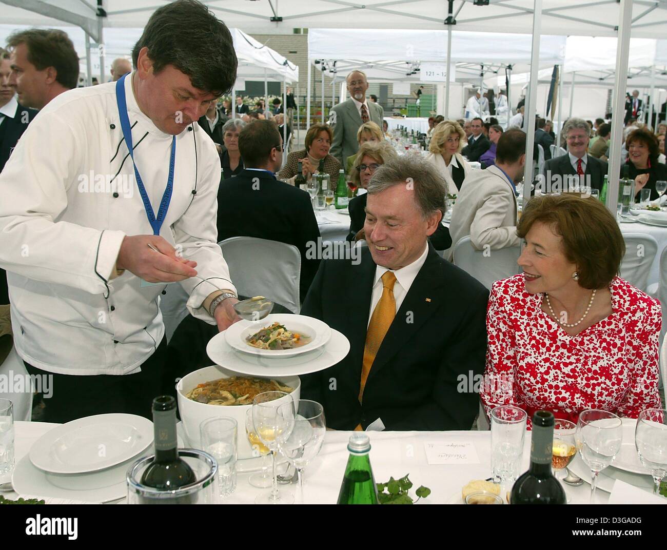 (dpa) - New German President Horst Koehler (C) and his wife Eva (R) look on as three-star chef Harald Wohlfahrt serves a German stew during Koehler's first public appearance as President during the 'Table of Democracy' dinner in front of Berlin's landmark Brandenburg Gate, 3 July 2004. The dinner, at which 1,200 citizens from eastern and western Germany took place, was organized to Stock Photo