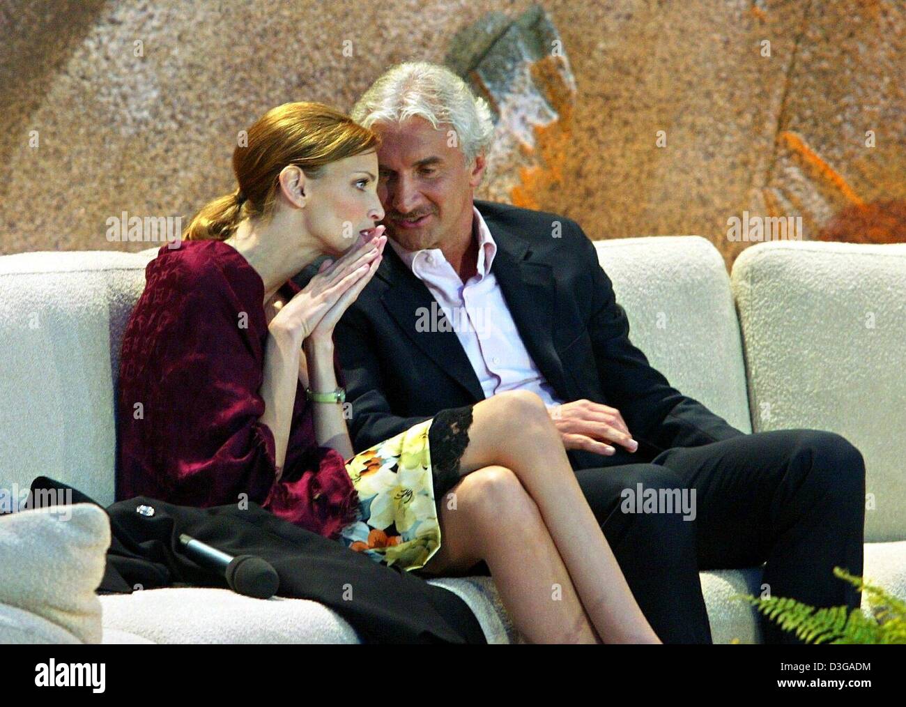 (dpa) - Former German national soccer coach Rudi Voeller, who had stepped down from his post in the wake of Germany's first round elimination at the Euro 2004 championships, chats with model Nadja Auermann sitting on a sofa on stage during the live German television show 'Wetten dass...?' (bet that...?) in Berlin, 3 July 2004. Stock Photo