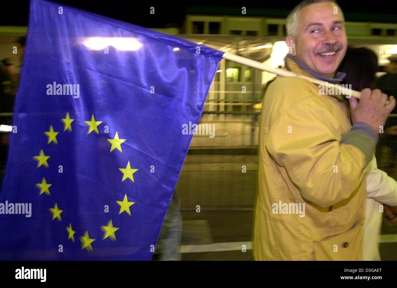 (dpa) - A Polish citizen carrying a EU flag crosses the German-Polish border in Ahlbeck-Swinemuende (Swinoujscie), 1 May 2004. On 1 May 2004 the European Union welcomed 10 new member states, including Czechia and Poland. Stock Photo