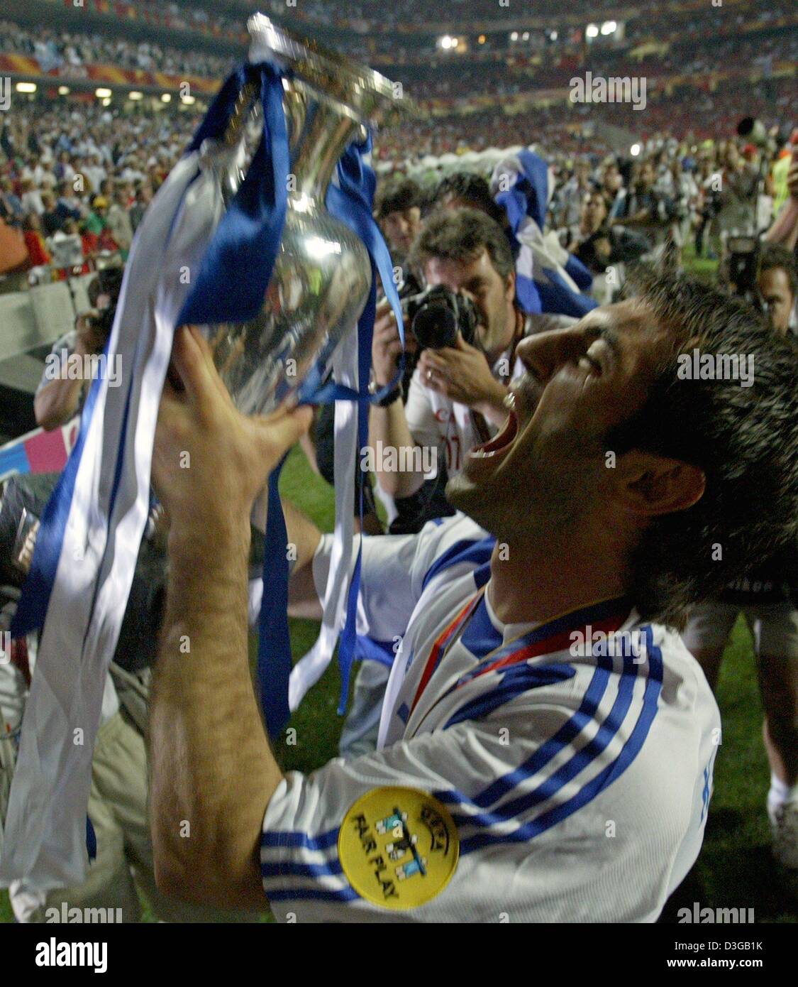 (dpa) - Greek midfielder Georgios Karagounis is surrounded by photographers as he holds up the trophy which is draped with the Greek colours after the Euro 2004 soccer final between Portugal and Greece at Luz Stadium in Lisbon, Portugal, 4 July 2004. Greece, which had never before won a European Championship or World Cup match, wrote footballing history with their memorable 1-0 vic Stock Photo