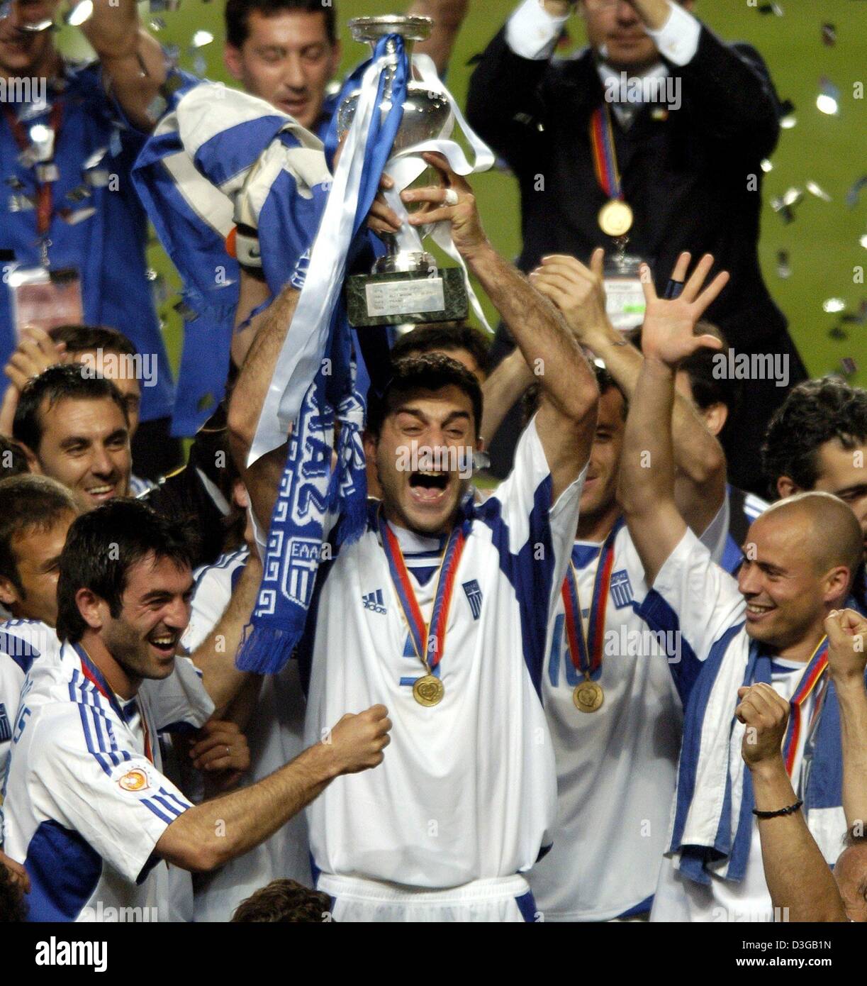 (dpa) - Cheering with his teammates Greek defender Traianos Dellas (C) holds up the trophy which is draped with the Greek colours after the Euro 2004 soccer final between Portugal and Greece at Luz Stadium in Lisbon, Portugal, 4 July 2004. On the left Georgios Karagounis, on the right Stylianos Giannakopoulos. Greece, which had never before won a European Championship or World Cup  Stock Photo