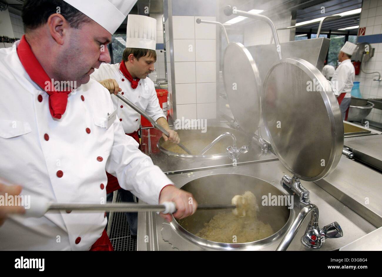 (dpa) - Chef Winfried Koepke (L) and cook Michael Birk stir large pots of food in the kitchen of the cafeteria at the university in Dortmund, Germany, 6 October 2004. Every morning at 7 a.m. seven cooks, the chef, his assistant and several other employees start their workday. The doors of the cafeteria open at 11.30 a.m. and a starved pack of people storms into the dining hall. One Stock Photo