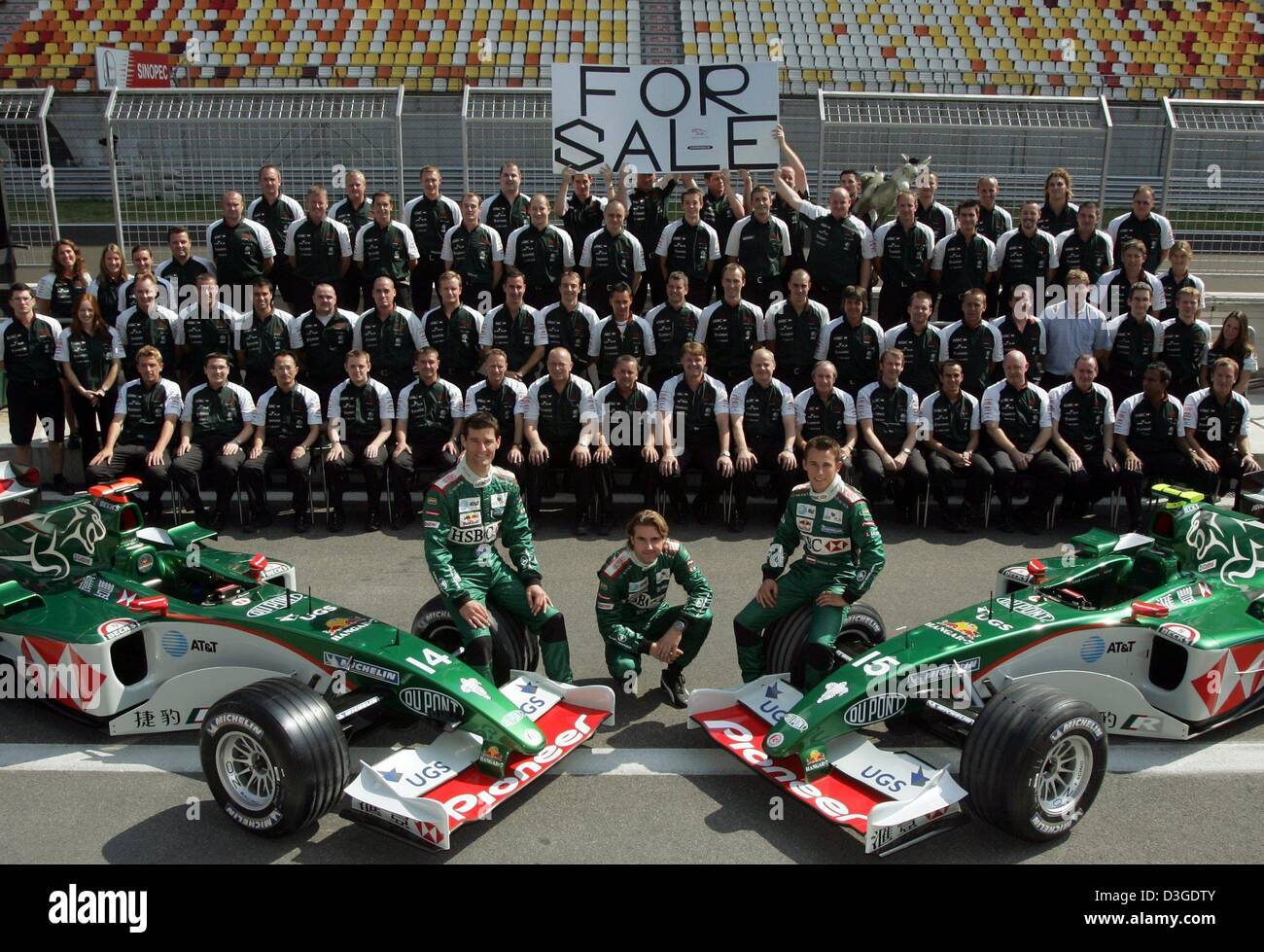 (dpa) - The Jaguar team with their formula one drivers Mark Webber, Bjoern Windheim and Christian Klien (L-R, front) pose with a 'For Sale' sign at the new formula one racing circuit in Shanghai, China, Thursday, 23 September 2004. Jaguar is to withdraw from Formula One racing from next season, the manufacturer's parent company Ford announced on Friday, 17 September. The announceme Stock Photo