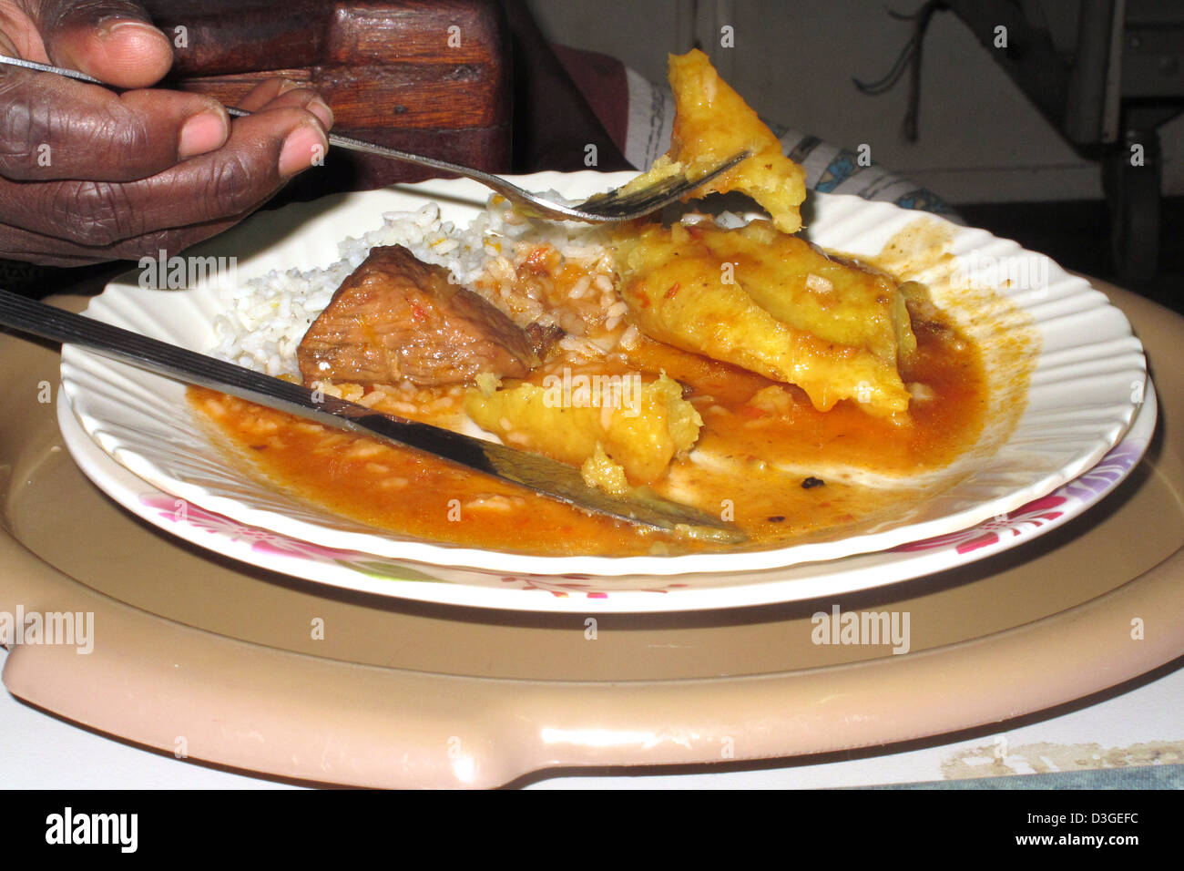 Eating a hospital meal consisting of beef, rice and matooke (plantain) in Mulago Hospital, Kampala Stock Photo