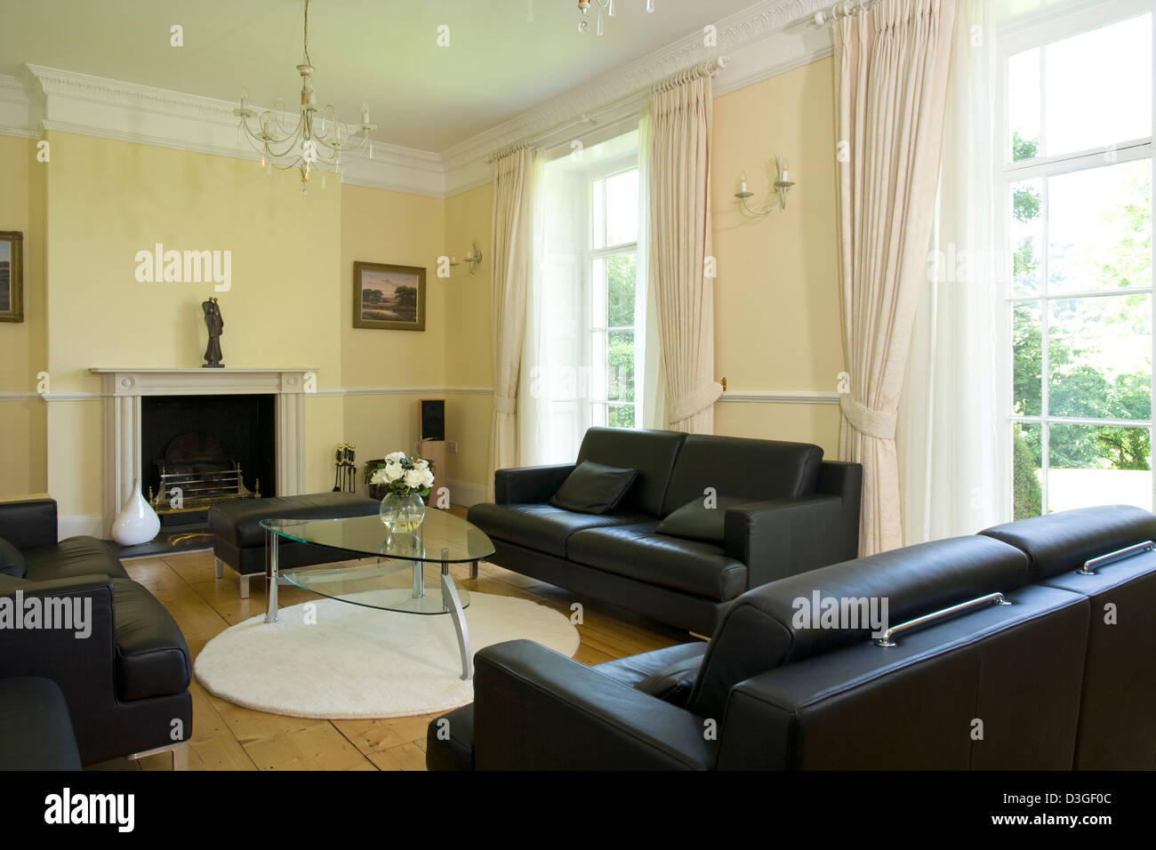 Modern dark leather sofas in an old high ceilinged sash windowed sitting room. Stock Photo