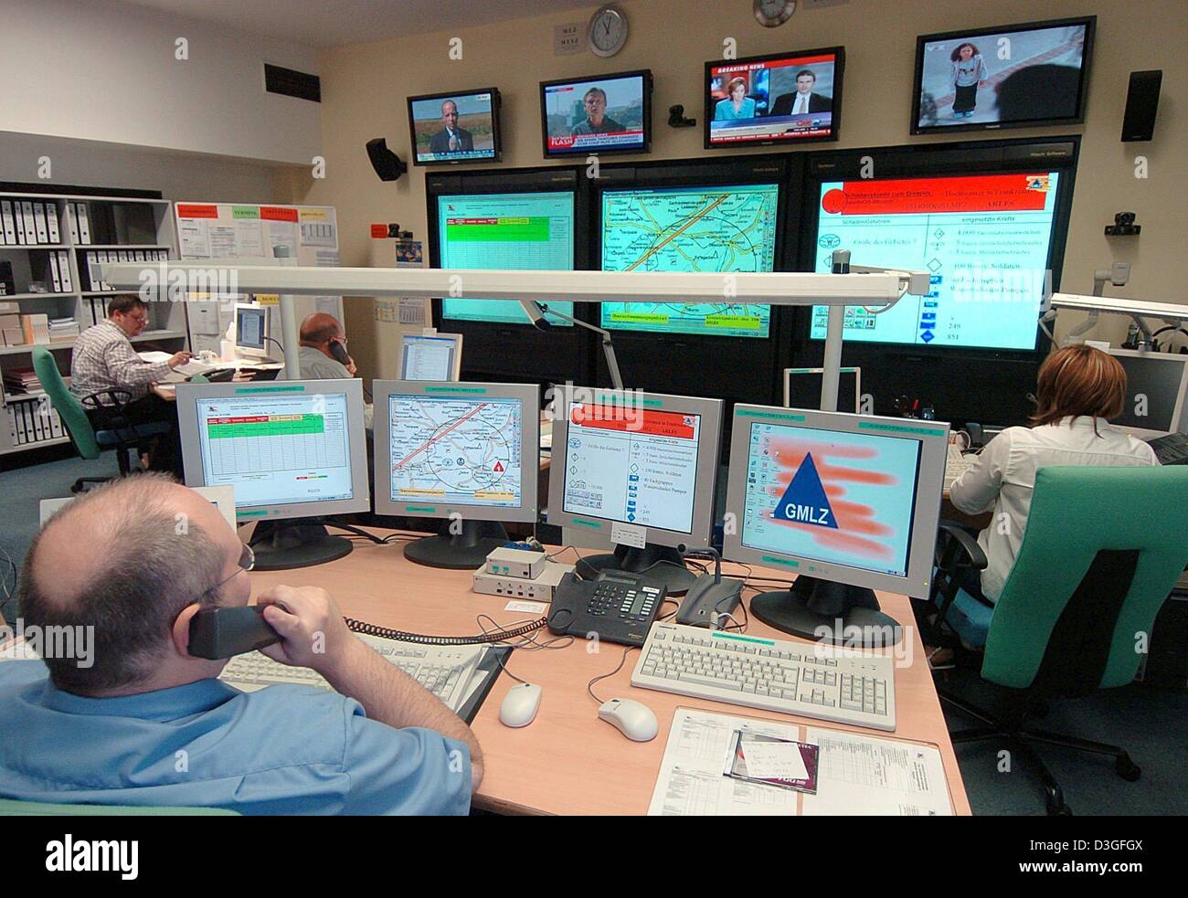 (dpa) - Employees observe newsfeeds and the several television and computer screens in the crisis center at the Federal Bureau of Civil Defence and Disaster Relief in Bonn, Germany, 25 August 2004. For the most part kept quiet from the general public, hundreds of security experts are training and preparing for 'day x'. Aside from natural desasters such as floods or storms, that day Stock Photo