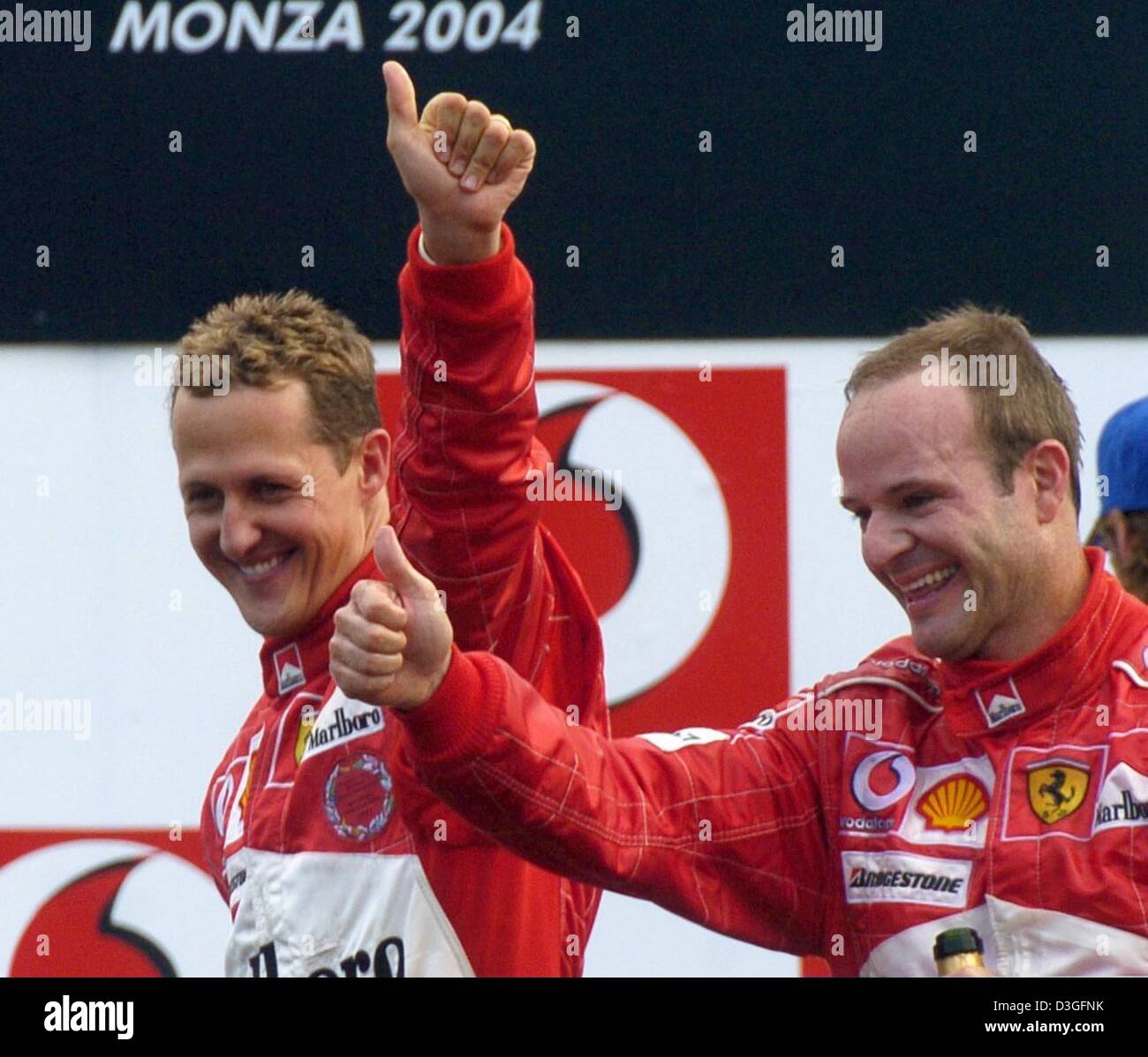 (dpa) - Ferrari Formula 1 drivers Rubens Barrichello (R) from Brazil and his German teammate Michael Schumacher (L) jubilate after the end of the Italian Grand Prix in Monza, Italy, 12 September 2004. Barrichello won the race with Schumacher coming in second to give Ferrari its 9th 1-2 finish of the current racing season. Stock Photo