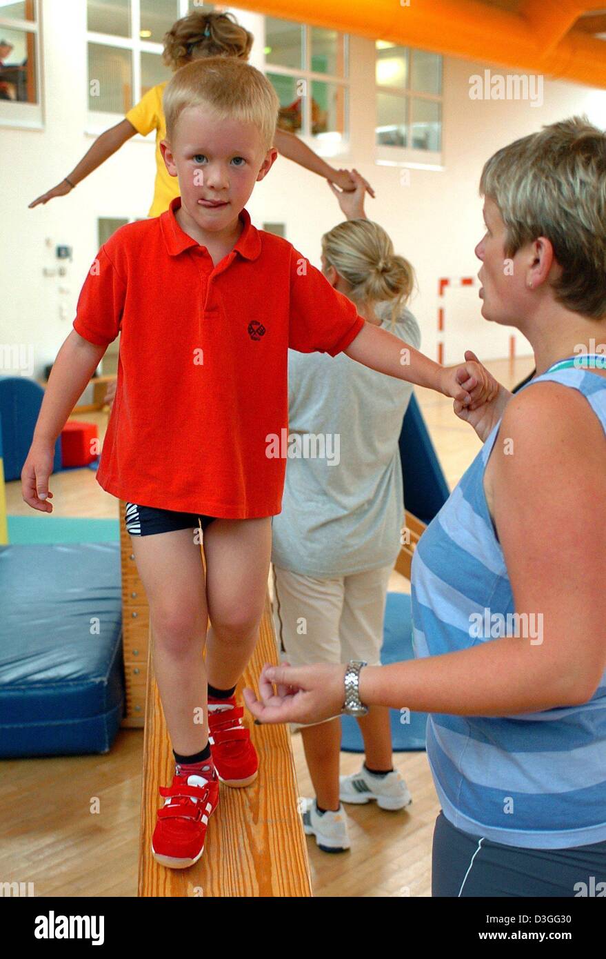 (dpa) - Birgit Niebuhr assists her son Tobias to balance on a bench in the gym of the Sanitas mother-child clinic at the health resort of Boltenhagen, Germany, 13 August 2004. The children are mainly treated for respiratory infections, skin diseases as well as psychosomatic illnesses. Stock Photo