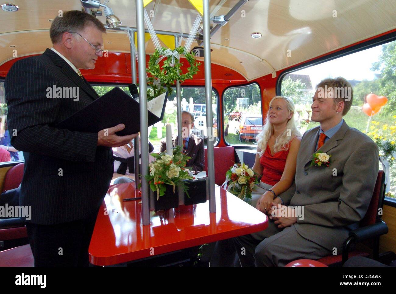 (dpa) - The wedding couple Gabriela Propp and Marc Neben are married by Flintbek's mayor and registrar Horst-Dieter Lorenzen (L) in a refurbished public transport bus in Kleinflintbek, Germany, 3 September 2004. They were the first couple to be married inside a bus of the public transport company KVG in Kiel. Stock Photo