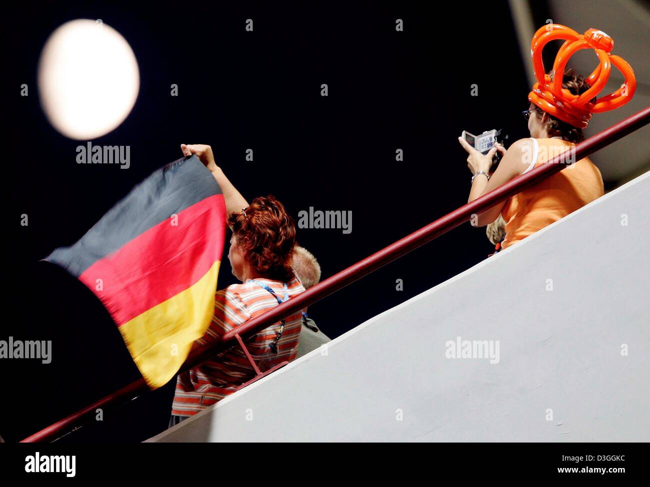 (dpa) - A German supporter is filmed by a Dutch supporter (R) as they watch the women's Hockey Final Netherlands vs. Germany under the bright moon at the Athens 2004 Olympic Games, Thursday 26 August 2004. Germany clinched a surprise gold in women's hockey by beating European champions the Netherlands 2-1 in the final Stock Photo