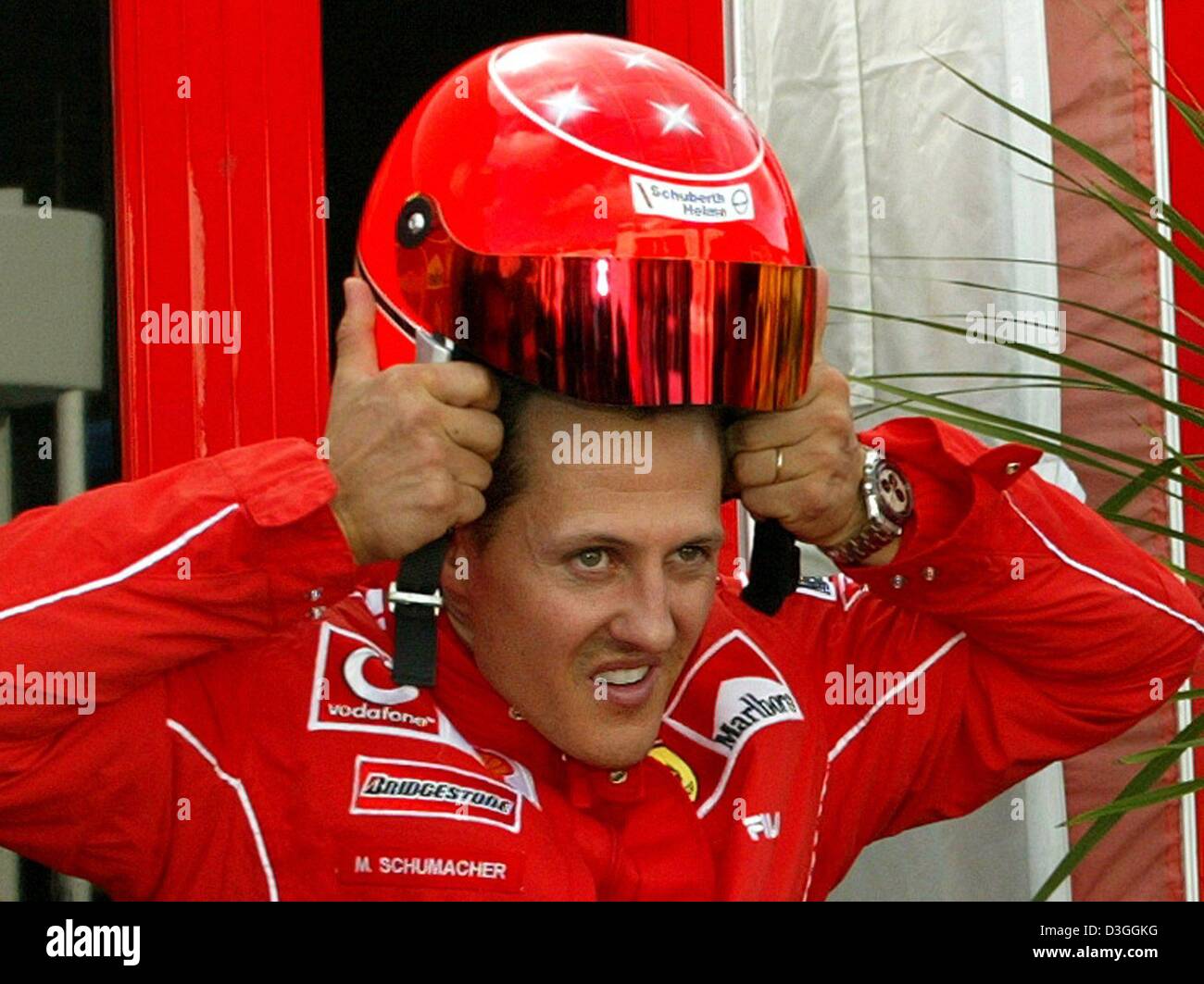dpa) - German formula one pilot Michael Schumacher of Ferrari puts on a  helmet for a ride on his motor scooter on the formula one racing track in  Spa-Francorchamps, Belgium, Thursday evening,