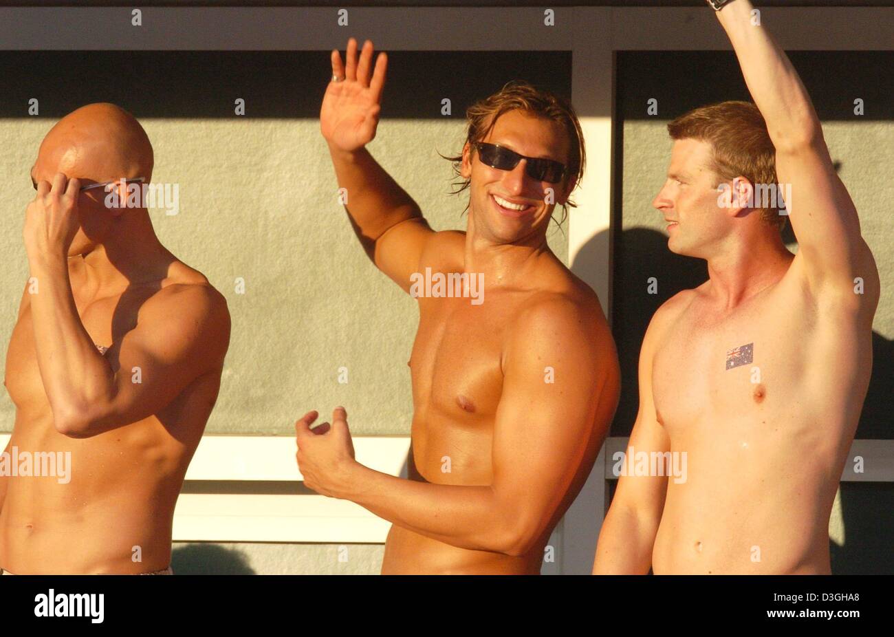 (dpa) - Australian swimmers Ian Thorpe (C), Michael Klim (L) and Regan Harrisson (R) wave to the crowd in the warm evening sunlight while watching the evening events at the Olympic Aquatic Centre in Athens, Greece, 19 August 2004. Stock Photo