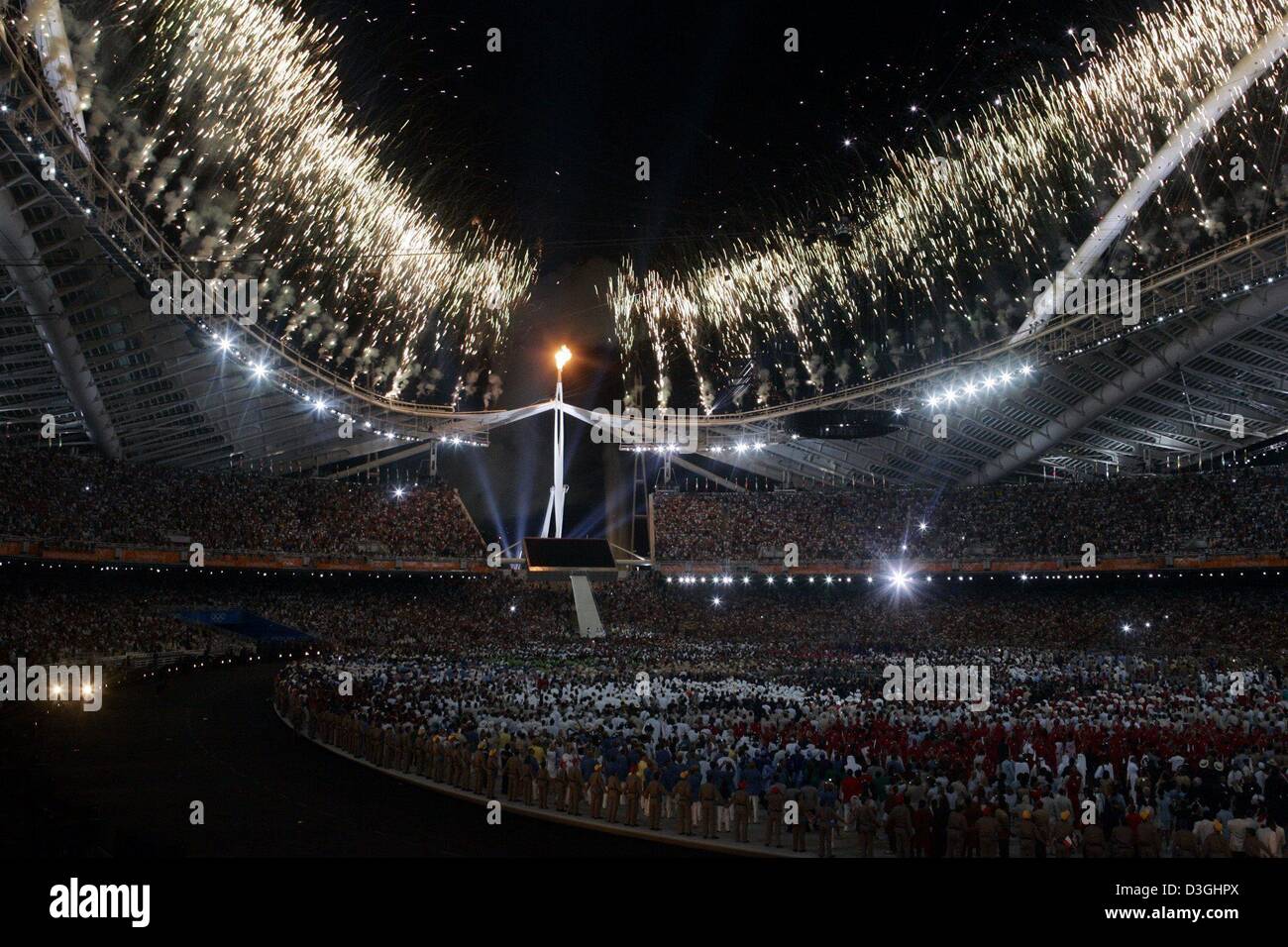 (dpa) - Fireworks illuminate the sky over the Olympic Stadium as the Olympic Flame is lit during the opening ceremony of the 2004 Olympic Games in Athens, Friday 13 August 2004. Stock Photo