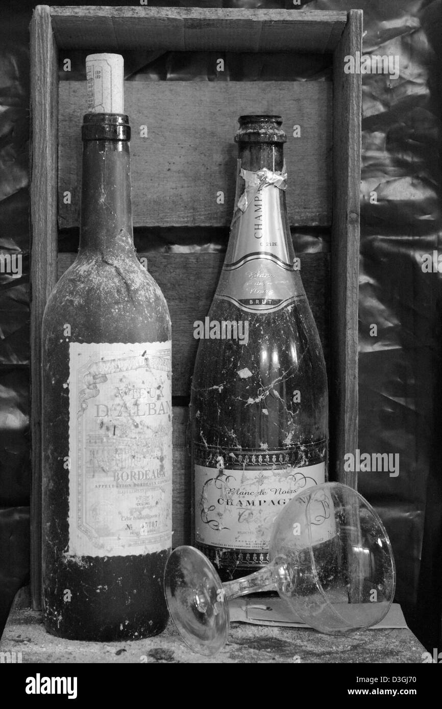Dusty wine and champagne bottles and an upturned champagne glass Stock Photo