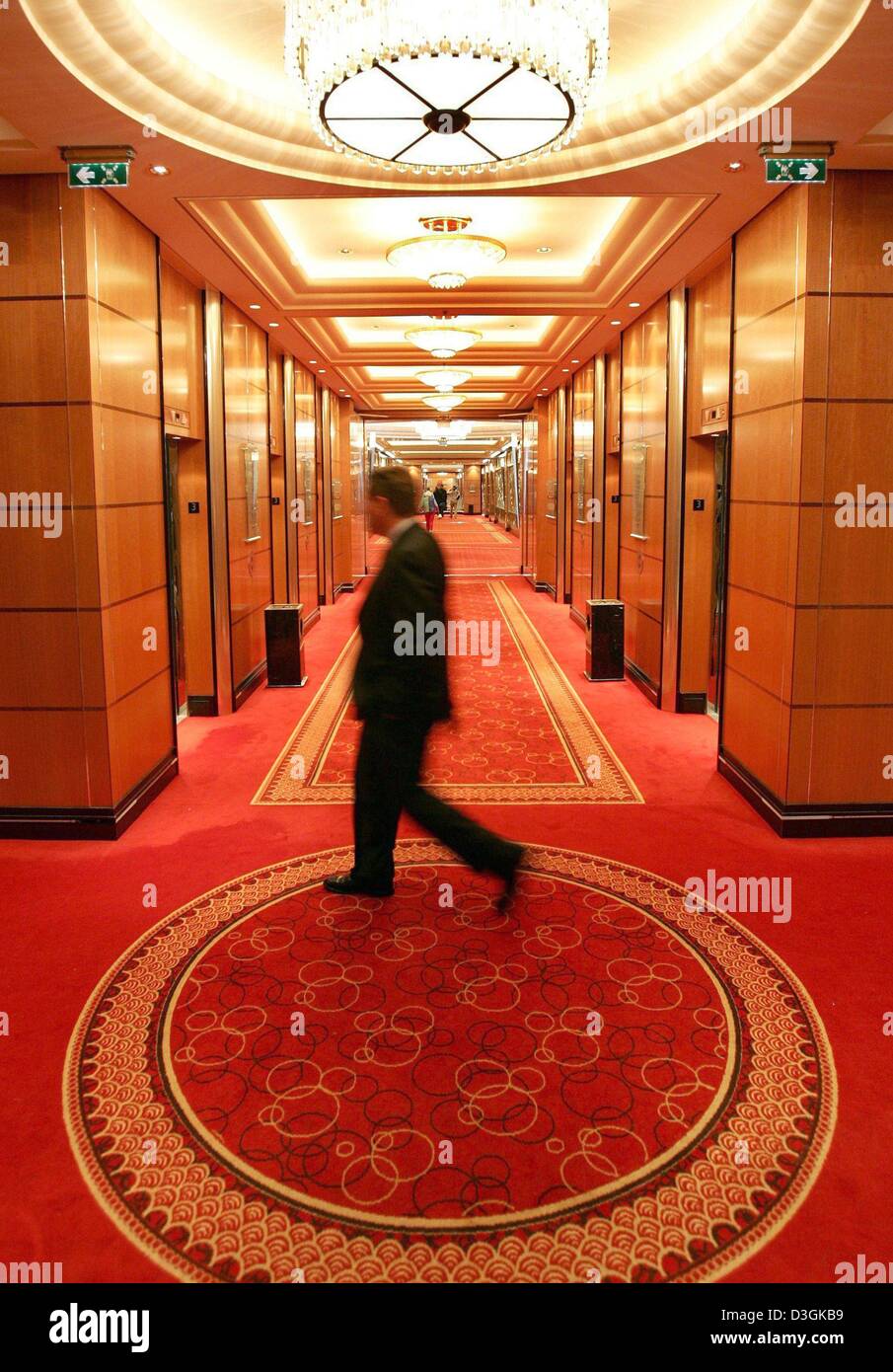 (dpa) - A passanger walks along a corridor on the luxury cruise liner 'Queen Mary 2' which is docking at the pier of the harbour in Hamburg, Germany, 19 July 2004. The 'Queen Mary 2', which was built at a cost of 800 million dollars, is the flagship of the British Cunard shipowning company. The vessel is 345 metres long, the length of the Eiffel Tower, and accommodates up to 2620 p Stock Photo