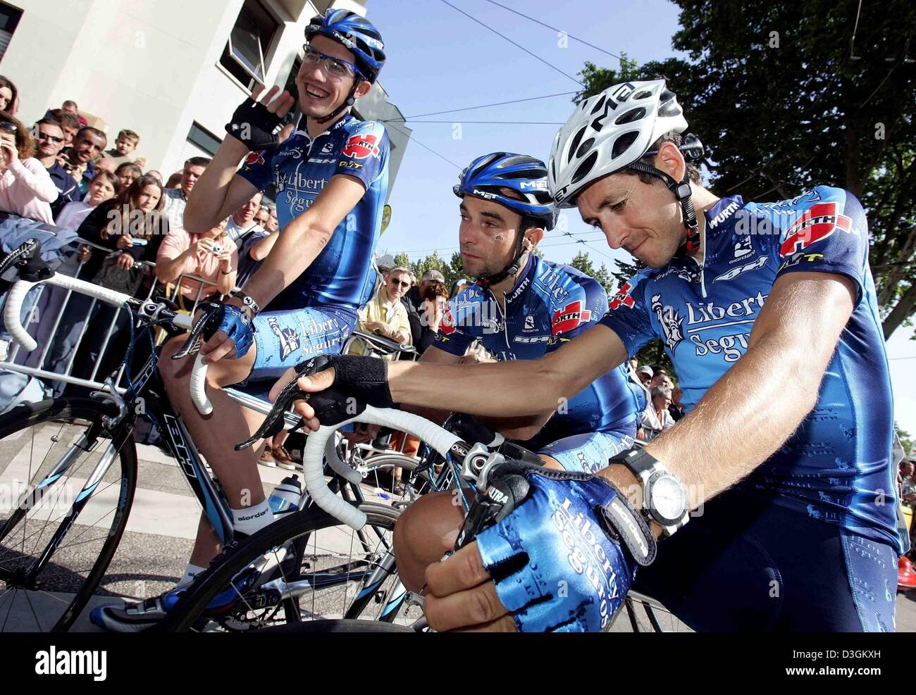(dpa) - The Spanish cyclists of team Liberty Seguros, Isidro Nozal (L-R), Angel Vicioso and Roberto Heras joke around as they ride to the start of the 10th stage of the Tour de France cycle race in Limoges, France, 14 July 2004. The first mountainous stage of the Tour leads through the Massif Central from Limoges to Saint-Flour. With 237 km it is also the longest stage of the 2004  Stock Photo
