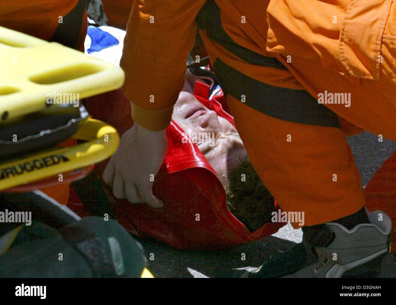 (dpa) - Paramedics and members of the safety team position German formula one pilot Ralf Schumacher of BMW-Williams on a stretcher after his accident during the US Grand Prix on the racetrack in Indianapolis, USA, 20 June 2004. Ralf Schumach ran with top speed of around 300 kilometres per hour into a barrier along the racetrack in the tenth lap of the race. He suffered several brui Stock Photo