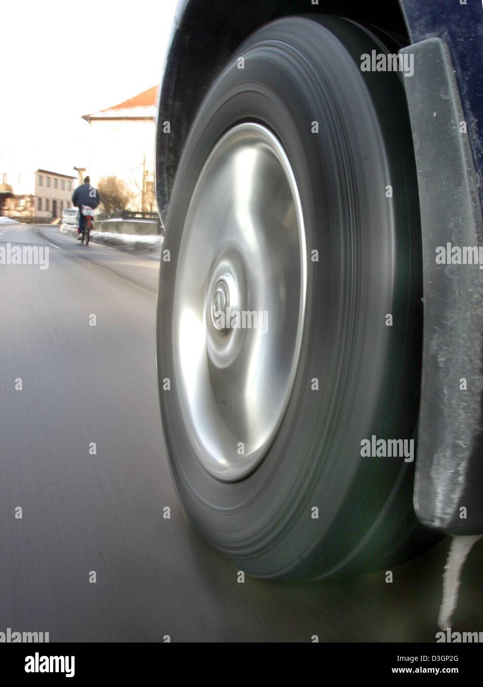 (dpa) - A giant car tyre seems to be chasing a tiny cyclist in Michelau, Germany, 22 January 2004. Stock Photo