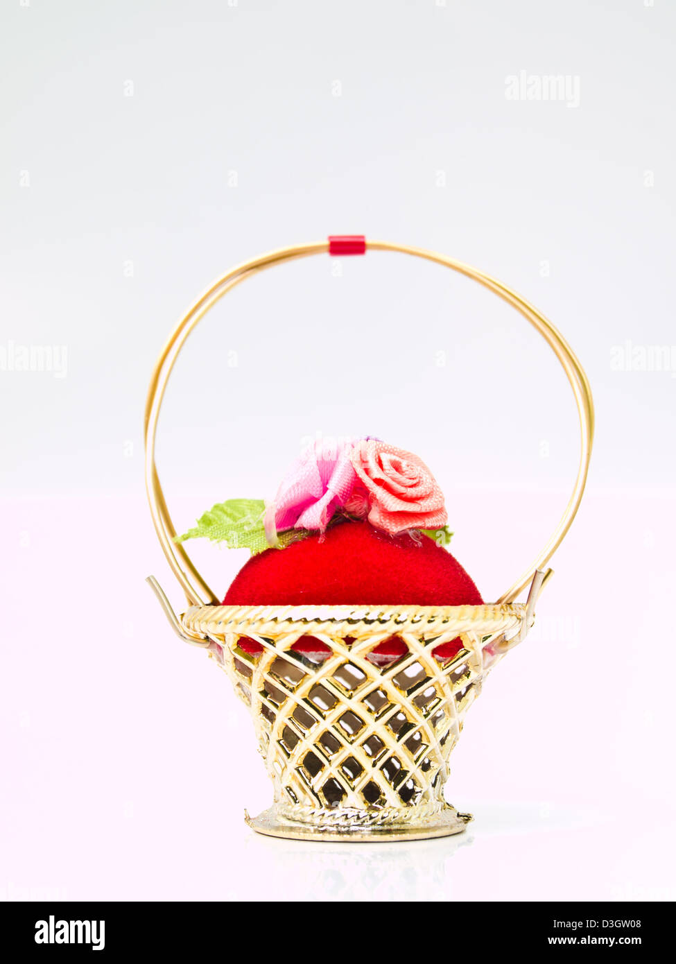 A miniature metallic wicker decorated by roses on a red velvet isolated on white background Stock Photo