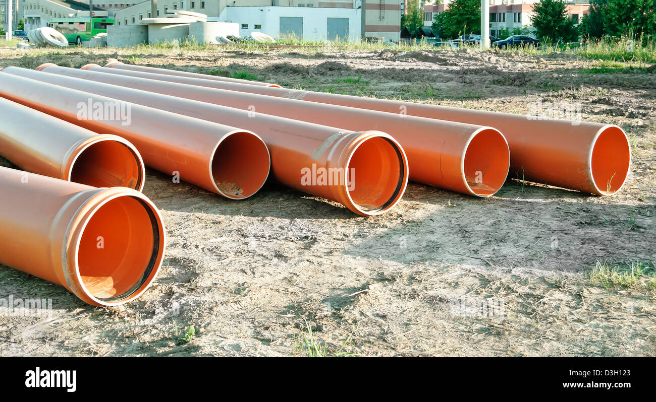 Several orange plastic pipes used in construction for drainage or the sewerage on a building