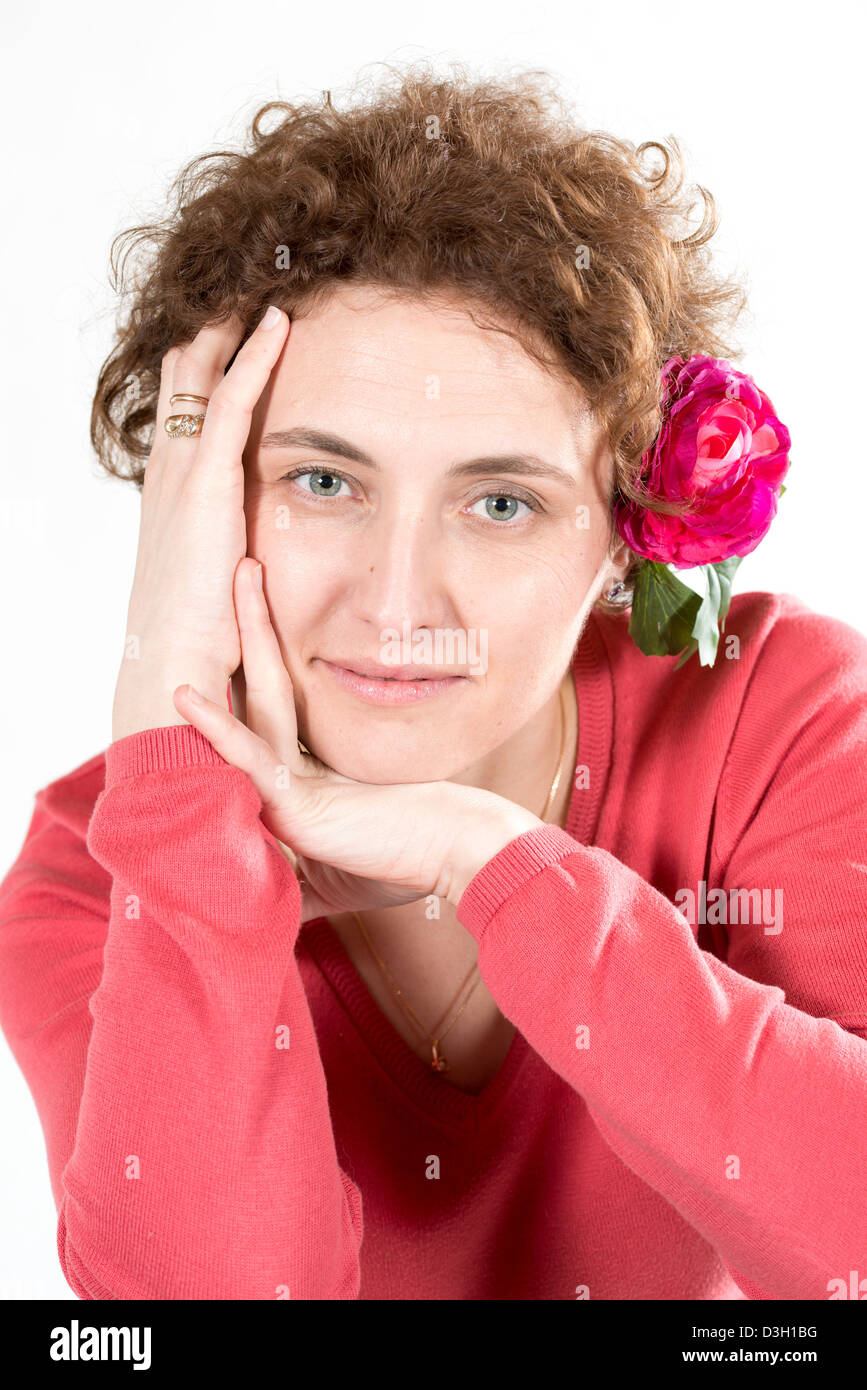 young curly woman wearing pink clothes and red flower in her hair Stock Photo