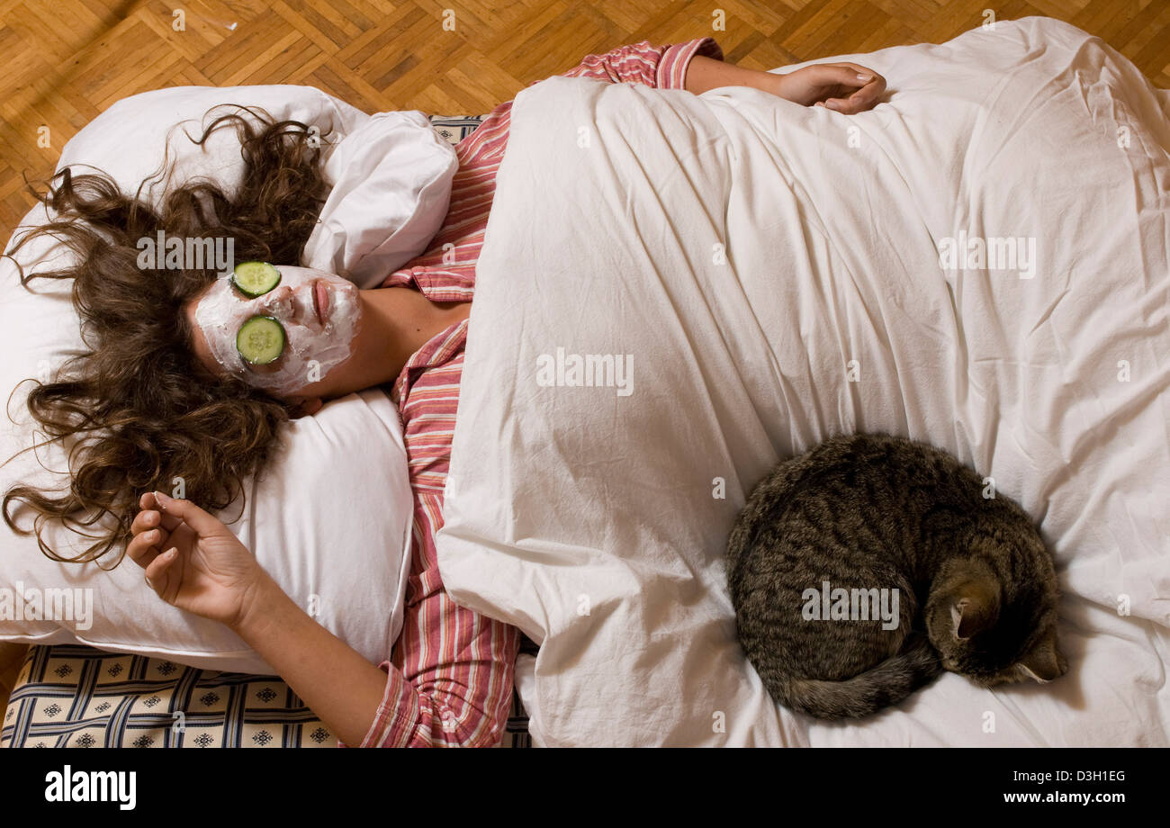Todtnau, Germany, is a woman with cucumber mask and cat in bed Stock