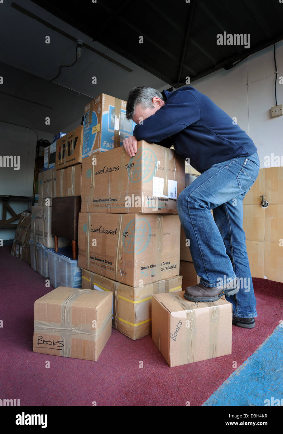 MAN  WITH HEAD IN HANDS WITH PILE OF REMOVAL BOXES RE HOUSE MOVE MOVING REPOSSESSION HOMELESS HOME EVICTION RELOCATION STRESS UK Stock Photo