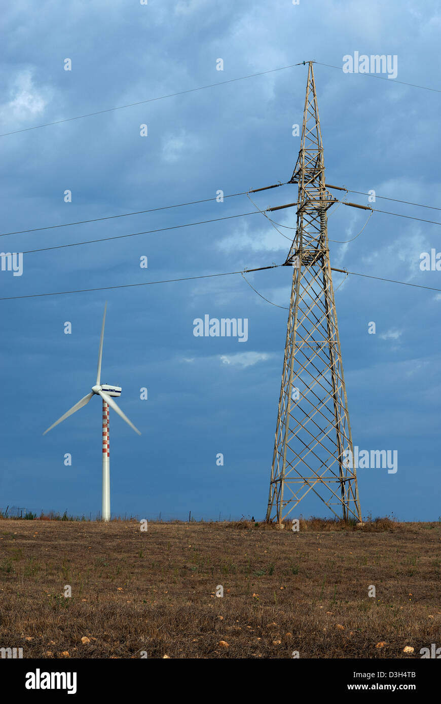 Porto Torres, Italy, power pole and the power utility Enel SpA Windmill Stock Photo