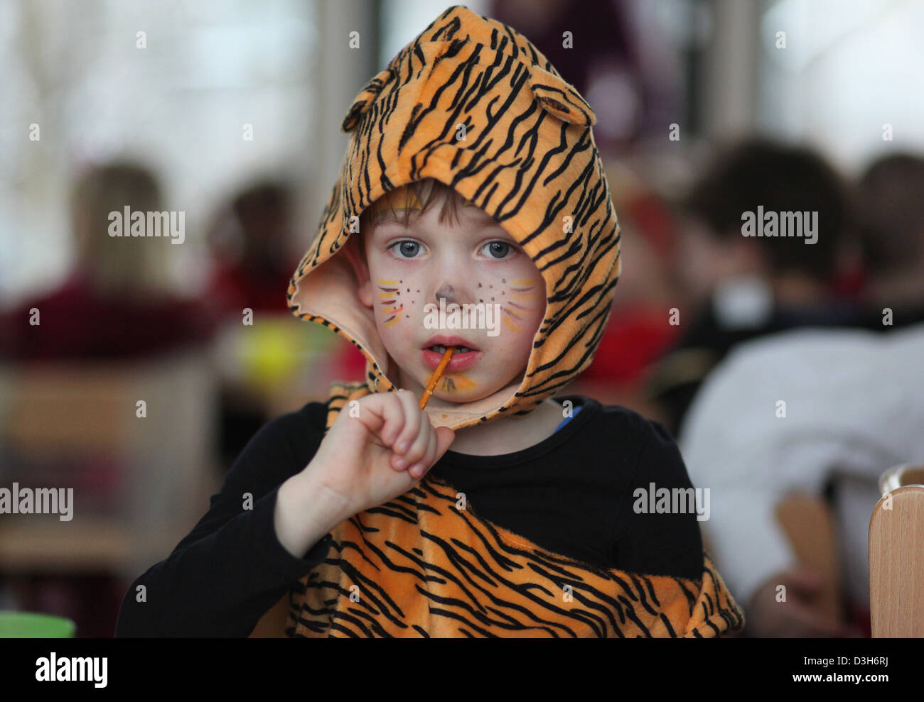 A German five year old boy dresses as a tiger eating a saltstick during a carnival party in the kindergarten. Leipzig, Germany Stock Photo
