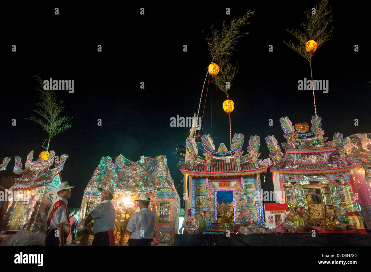Men praying to houses built for their ancestors during the Chinese 'Ghost festival' in Keelung, Taiwan Stock Photo