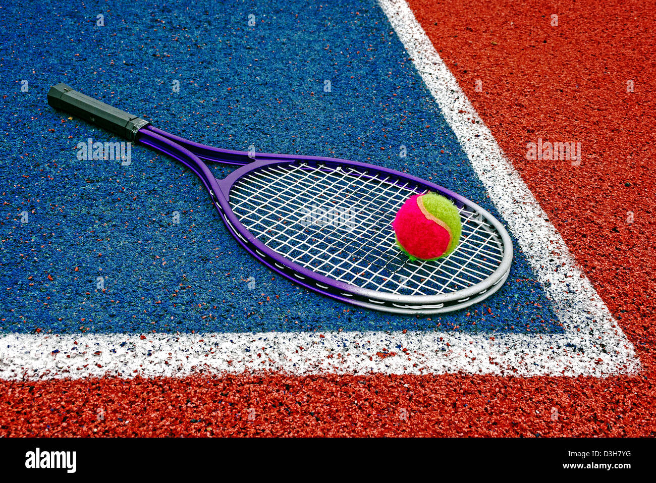 Tennis colored ball and racket, placed in the corner of a synthetic field  Stock Photo - Alamy