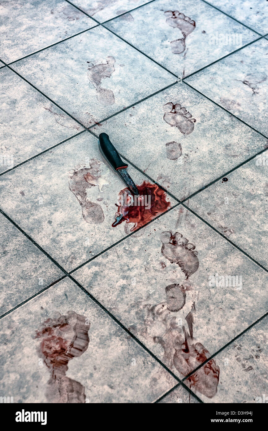 bloody foot prints and a knife in a pool of blood on a bathroom floor Stock Photo