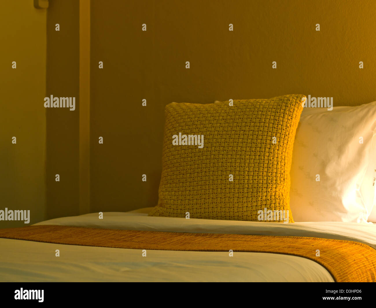 A design yellow pillow in a modern style bedroom interior with warm light Stock Photo