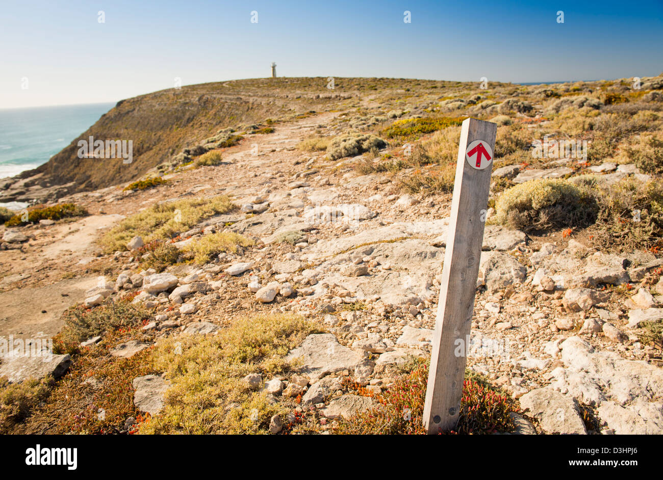 Arrow on signpost points the direction along the cliffs to the distant lighthouse Stock Photo