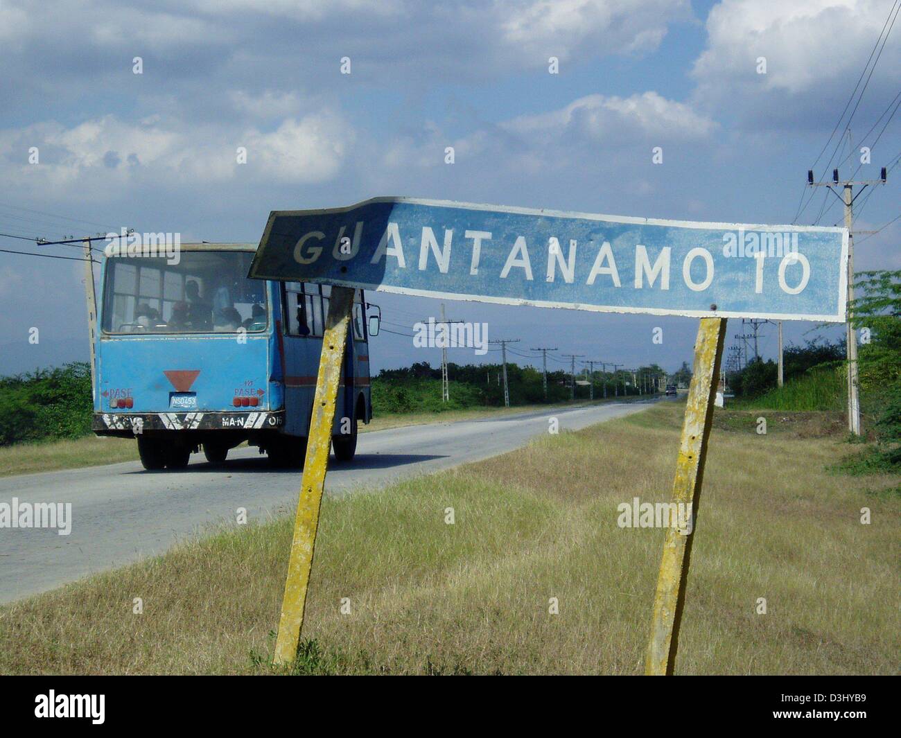 (dpa) - A bus drives past a road sign which reads 'Guantanamo 10' near Guantanamo on the island of Cuba, 25 January 2004. Only very few cars travel along the roads between the restricted area surrounding the US military base and the closest village Caimanera which can only be accessed with a special permit. Stock Photo
