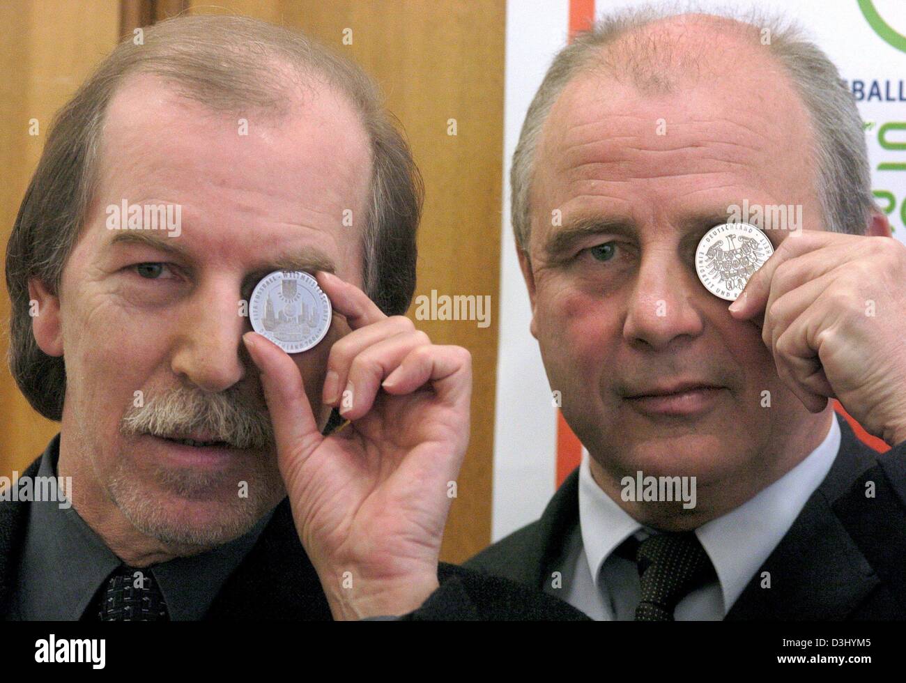 (dpa) - German soccer legends and current World Cup ambassadors Juergen Grabowski (L) and Bernd Hoelzenbein present the first issued commemorative coins for the 2006 World Cup in Frankfurt Main, Germany, 28 January 2004. The coins feature some of Frankfurt's landmarks such as the skyline, the Roemer (town hall) and the fair centre along with symboles of the World Cup. Stock Photo