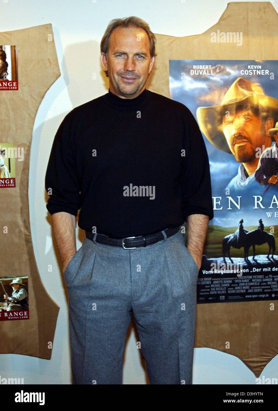 (dpa) - US actor and director Kevin Costner smiles as he poses in front of a poster which advertises his latest film 'Open Range' shortly before the premiere of Kostner's film in Hamburg, Germany, 23 January 2004. The film will be officially released in Germany on 29 January 2004. Stock Photo