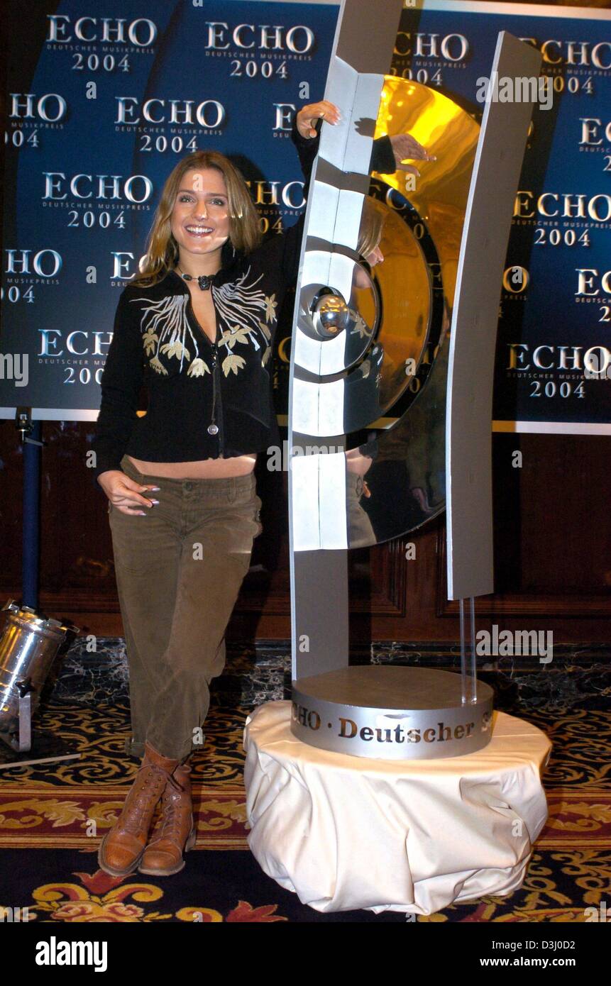 (dpa) - German pop singer Jeanette Biedermann smiles as she poses with an enlarged replica of the Echo award trophy during a press conference in Berlin, 15 January 2004. Biedermann is among the nominees for this year's Echo award. Other candidates for the award are Justin Timberlake, Robbie Williams, Pink and German 'Superstar' winner Daniel Kueblboeck, among others. The 'Echo' is  Stock Photo
