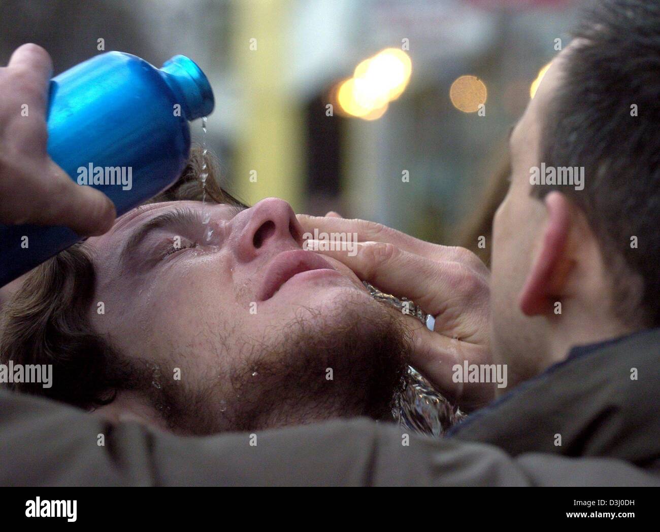 (dpa) - A protester washes out the eyes of a fellow protester with water  during a rally at the Berlin House of Representatives in Berlin, 15 January 2004. According to statements of witnesses, police had cornered some protesters in a backyard and used teargas on them. Around 1,000 protesters gathered for a rally at the Berlin House of Representatives in order to voice their protes Stock Photo