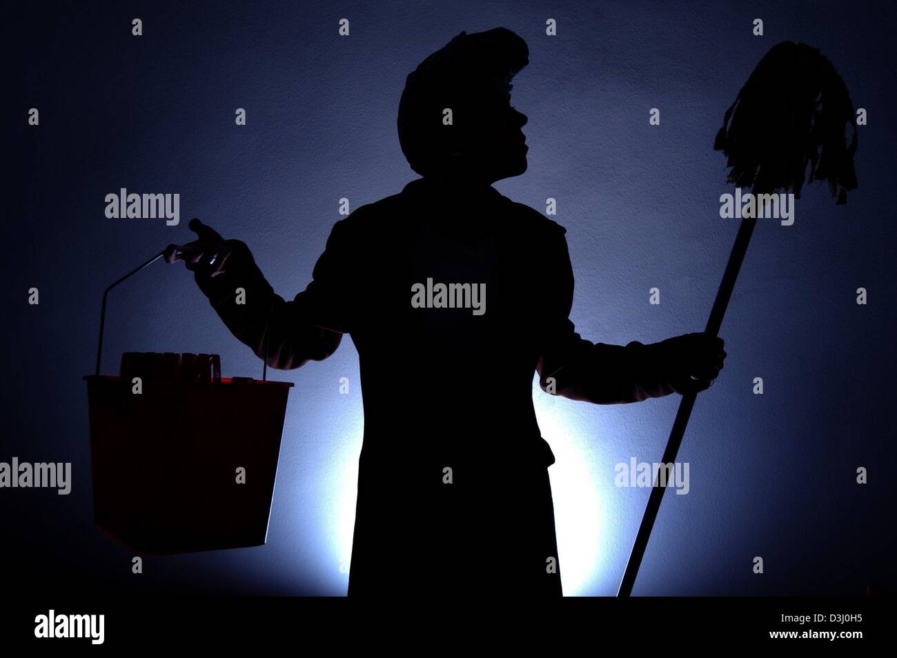 (dpa) - The symbolic photo shows the silhouette of a cleaning woman holding up a bucket and a mop, photographed against a light in Potsdam, Germany, 12 January 2004. In Germany, illicit employment and moonlighting will in the future be punishable. Those who illegally employ a cleaning woman or craftsmen without invoice, will be subject to criminal prosecution and can be punished wi Stock Photo