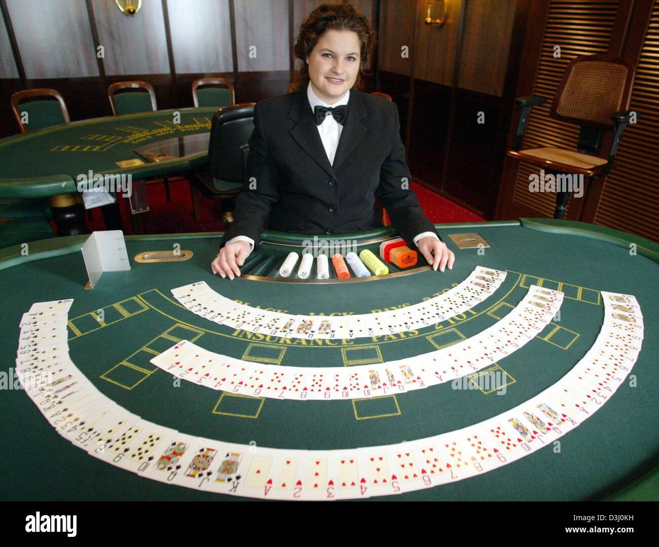 Woman croupier near card table in casino offers to play black jack or  preference and try luck in Las Vegas. Croupier girl in elite poker club or  casino helps to enjoy gambling