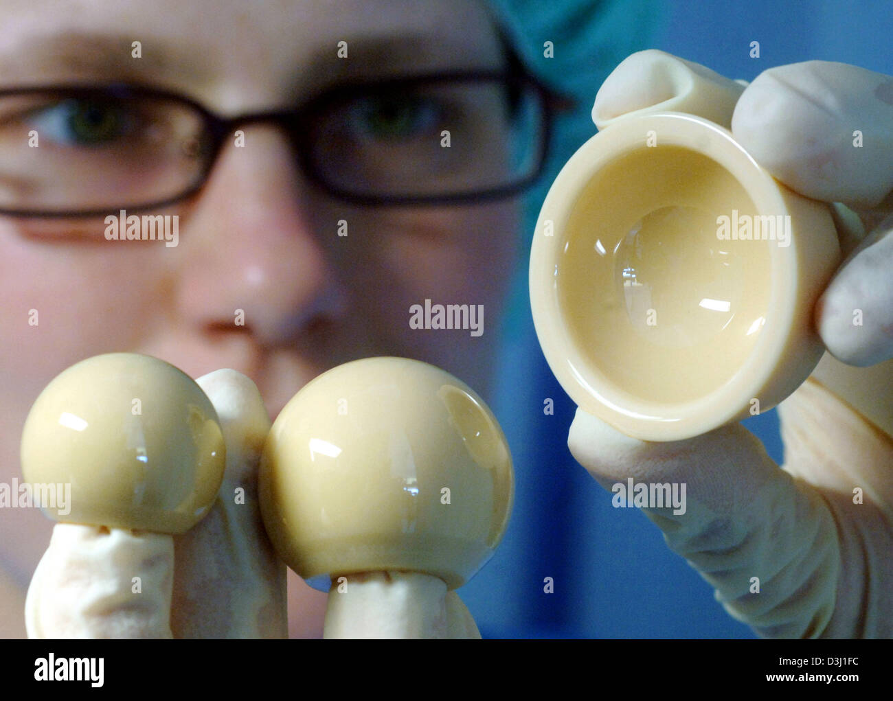 (dpa) - Artificial hip joint balls made of bioceramic with an enlarged diameter of 36 millimetres are the latest development of Mathys Orthopädie GmbH in Moersdorf, Germany, 24 June 2005. Staff member Anne Arnold shows a swivel head with its socket at a sterile working station. On the left a conventional hip joint ball with a diameter of 28 millimetres. The risk of dislocating the  Stock Photo