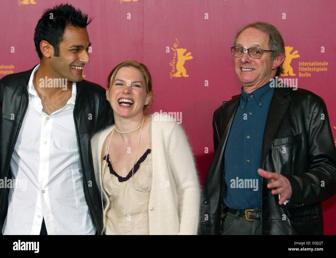 (dpa) - British actors Eva Birthistle and Atta Yaqub and british filmmaker ken Loach stand next to each other and smile as they attend a press conference during the 54th Berlinale International Film Festival in Berlin, 13 February 2004. Birthistle, Yaqub and Loach presented their new film 'A Fond Kiss'. The film tells the love story between a young Catholic woman from Glasgow and t Stock Photo