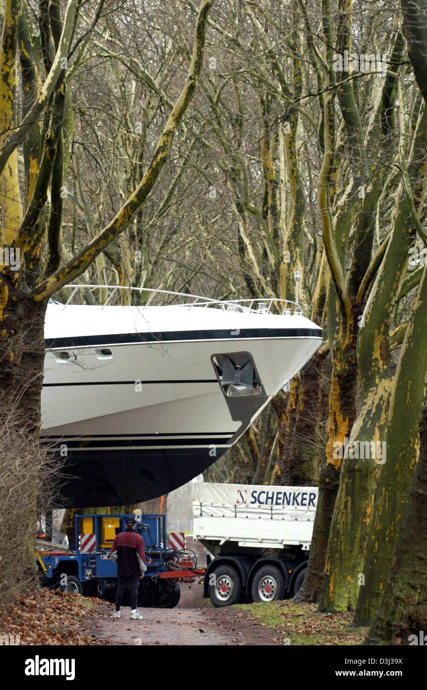 (dpa) - A jogger stands in front of the bow of a 'Mangusta 108 Open' motor yacht which is being carried by a heavy goods vehicle across a country lane on its way to the water sports fair 'Boot 2004' in Duesseldorf, Germany, 13 Januar 2004. The yacht is 33 metres long, weighs 130 tons and will be the largest exhibit featured at the water sports fair. The fair will last from 17 Janua Stock Photo