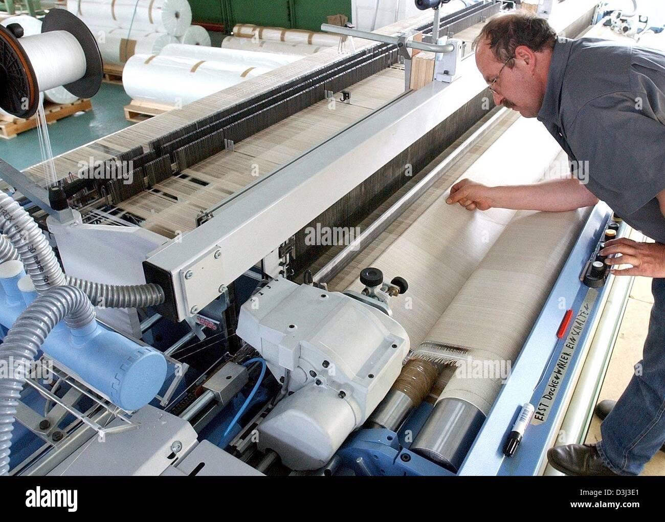 (dpa files) - Weaver Heinz Behrens shows a textile piece produced by a computer-controlled loom at the 'P-D aitec' company in Bitterfeld, eastern Germany, 26 June 2003. The company belongs to the Preiss-Daimler group and produces a patented impregnated glass fibre textiles, which are especially durable and enduring. The textiles are equally used in the space travel industry and the Stock Photo