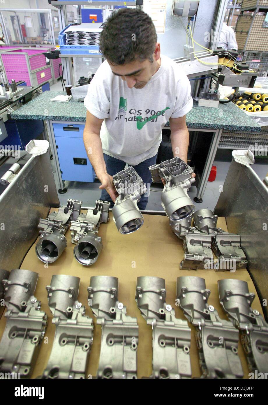 dpa - An employee shows oil housings, which are used for car production, at the Mann+Hummel car part supplier in Ludwigsburg, Germany, 26 May 2003. 'Mann and Hummel' is among