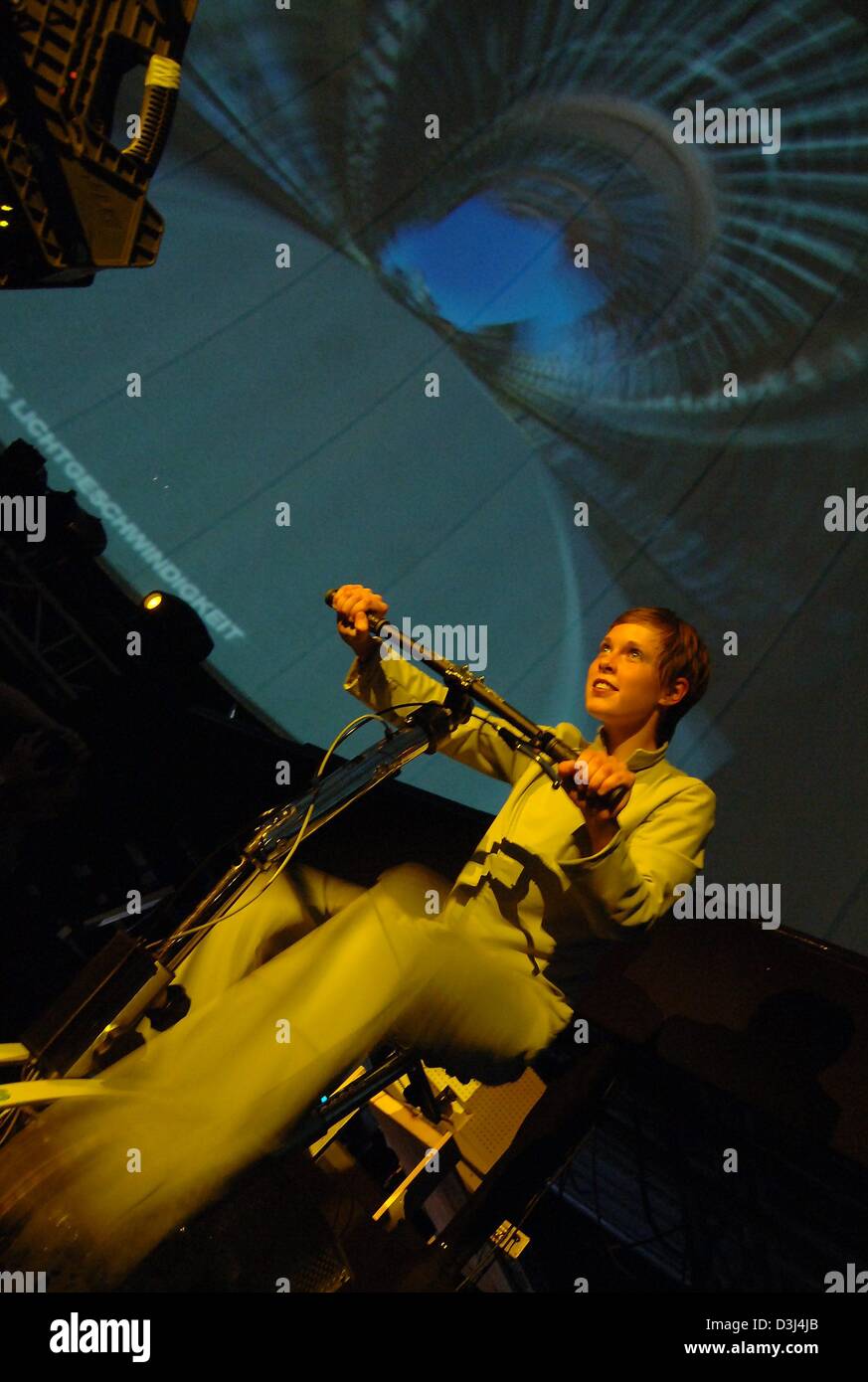(dpa) - Female dancer Peggy Ziehr sits on a modified trim bike during the dress rehearsal of the cross media opera 'C - the speed of light' in Berlin, Germany, Friday 10 June 2005. The opera about the life of Albert Einstein has public premiere on Saturday, 11 June 2005. Stock Photo